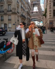 two women walking down the street in front of the eiffel tower