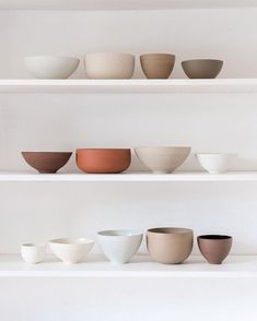 the shelves are filled with bowls and plates on top of each other in different colors