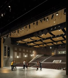 several people are standing in the middle of an empty auditorium with lights hanging from the ceiling