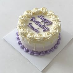 a birthday cake with white frosting and purple icing