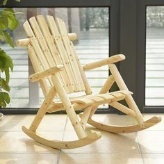 a wooden rocking chair sitting on top of a tile floor next to a potted plant