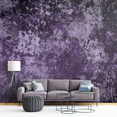 a living room with a couch, table and lamp in front of a purple wall