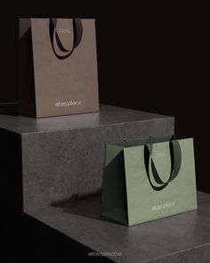 two shopping bags sitting on top of each other in front of a black background with the words at any place printed on it