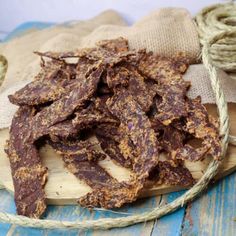 some kind of food that is on a wooden board next to twine and rope