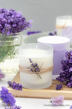 two candles are sitting on a table with lavender flowers