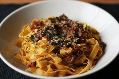 a white bowl filled with pasta and meat