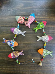 six colorful birds are arranged in a circle on a wooden table with beads and bead