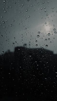 rain drops on the window and dark sky in the background, with buildings behind it