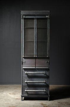 a tall black cabinet with metal handles and drawers on the bottom, against a dark background