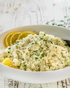 a white bowl filled with rice and lemon wedges