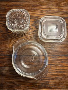 three clear glass dishes sitting on top of a wooden table next to an empty one