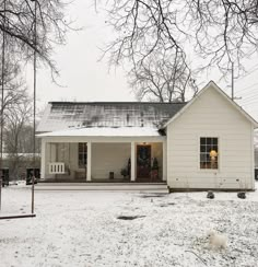 a white house sitting in the middle of a snow covered yard with a dog walking by