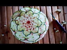 an art work made out of cucumbers on a wooden table next to a knife