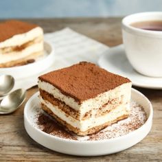 there is a piece of cake on the plate next to a cup of coffee and spoon