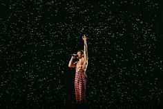 a man standing on top of a stage with his arms up in the air while holding a microphone