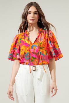 Rock this groovy floral print wherever you go. The Idalia floral print features multi-colored boho florals against a vibrant orange-ground. It decorates the Dupont top, a split neckline with short flouncy sleeves. It maintains a relaxed fit and can be tied at the neck and tucked into high waisted linen pants.- Flouncy sleeves- Split neckline- Ruffle trim- Relaxed fit- Color: Orange FloralSize + Fit - Model is 5'9" and wearing size S- Measurements taken from size S - Chest: 19 1/2"- Length: 25" F Colorful Tops Outfit, Printed Tops Designs, Groovy Outfit Women, Orange Top Outfit, Floral Shirt Outfit, Floral Top Outfit, Flouncy Sleeves, High Waisted Linen Pants, Unique Sewing Patterns