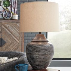 a table lamp sitting on top of a wooden table next to a chair and ottoman