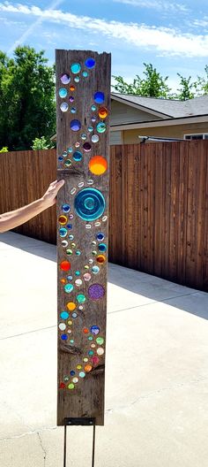 a person standing next to a tall wooden board with different colored circles painted on it