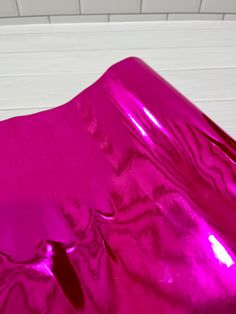 a shiny pink sheet is laying on the floor in front of a white wall and ceiling