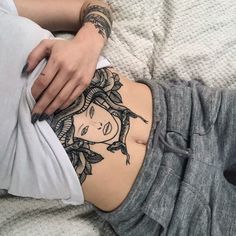 a woman laying on top of a bed covered in tattoos