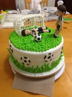 the cake is decorated with grass and soccer balls