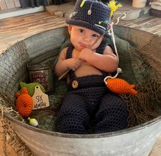 a little boy sitting in a bucket with some crocheted toys on the floor