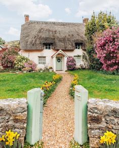 a house with a thatched roof and flowers in the front yard next to it