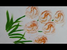 an orange and green painting on white paper with flowers in the middle next to it