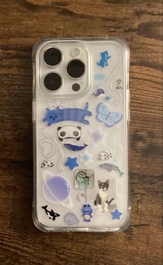 an iphone case with various stickers on the front and back cover, sitting on a wooden surface