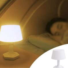 a lamp that is sitting on top of a table next to a person in bed