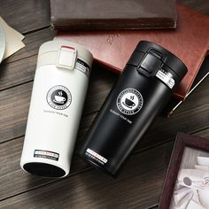 two black and white coffee mugs sitting on top of a wooden table