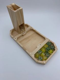 a wooden tray with dices in it on a white surface, next to a bottle opener