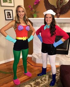 two women dressed in costumes standing next to each other on a wooden floor near a fireplace