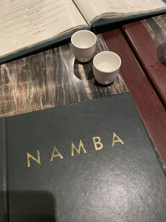 a table with a book, two cups and an open book on it that says nammba