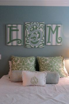 a white bed topped with pillows next to two framed monogrammed pictures on the wall