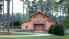 a small wooden building sitting in the middle of a lush green field next to trees