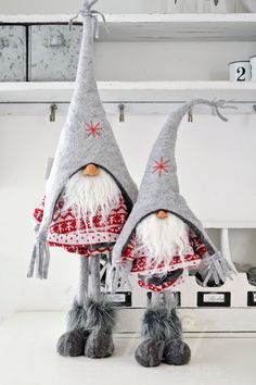 two gray and white gnomes are standing next to each other on a shelf in the kitchen