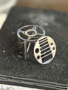 a metal object sitting on top of a black table next to a book with writing underneath it