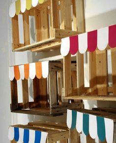 several wooden shelves with different colored paper hanging from the top, and below them is a white wall