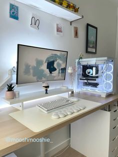 a desk with a computer monitor, keyboard and mouse on it in front of some pictures