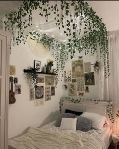 an unmade bed with plants hanging from the ceiling