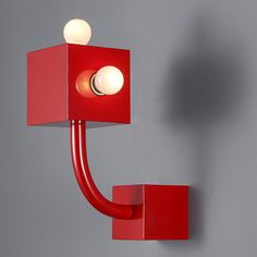 a red wall light with two white balls on it's head and an arm