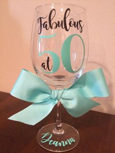 a wine glass with the number 50 on it and a blue ribbon tied around it