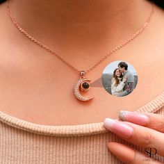 a woman's hand holding a necklace with an image of a couple on it