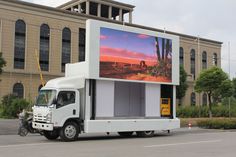 a large truck parked in front of a building with a billboard on it's side