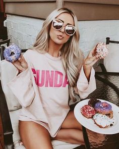 a woman sitting on a chair holding two doughnuts