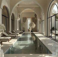 an indoor swimming pool with sun loungers and flowers in vases next to it