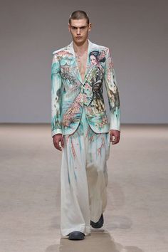 a man in a suit and tie walking down a runway