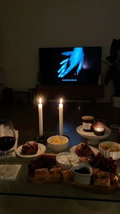 a table topped with food and candles next to a flat screen tv