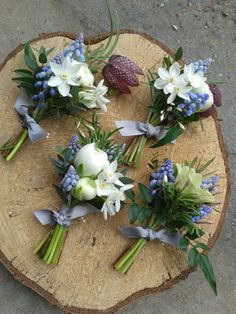 flowers are arranged on top of a piece of wood with blue and white ribbons around them